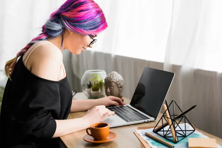 A builder working at a laptop at a sunlit desk